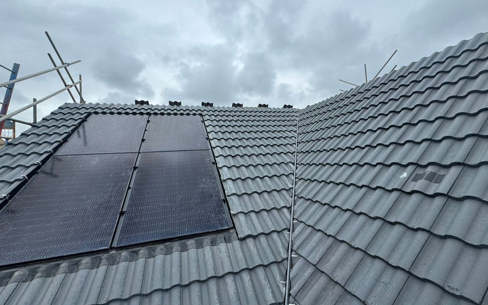 A tiled roof with solar panels fitted, photographed from the scaffold